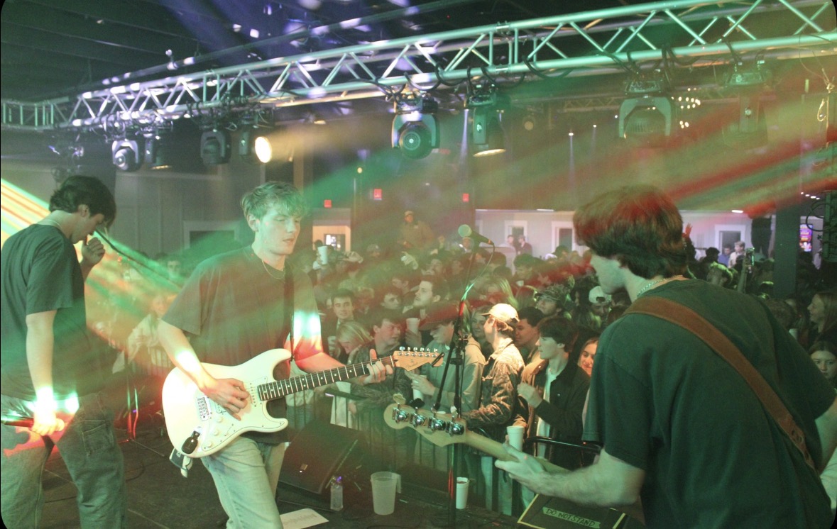 Band performing under stage lights for a college crowd